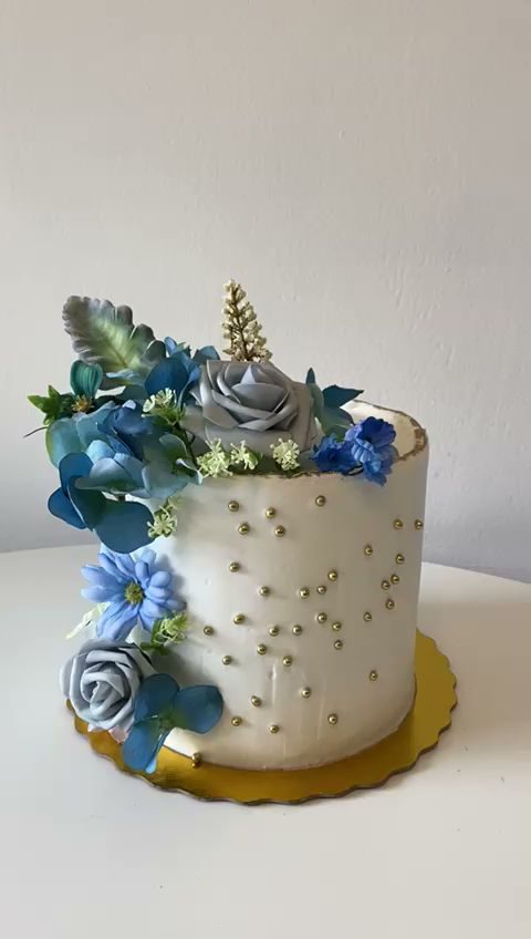 White cake with blue and grey flowers and gold dots